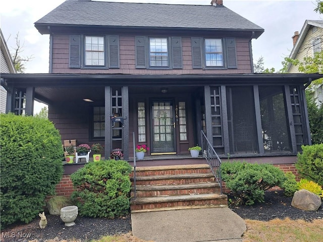 view of front facade with roof with shingles and a sunroom