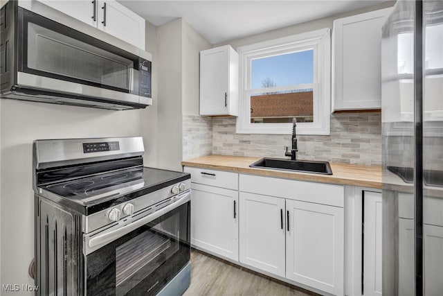 kitchen with a sink, butcher block countertops, tasteful backsplash, and stainless steel appliances