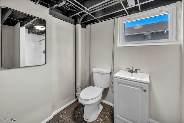 bathroom featuring concrete floors, baseboards, toilet, vanity, and a shower