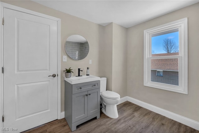 bathroom with vanity, toilet, wood finished floors, and baseboards