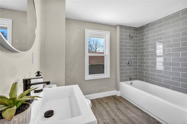 full bath with wood finished floors, shower / bathtub combination, baseboards, and a sink