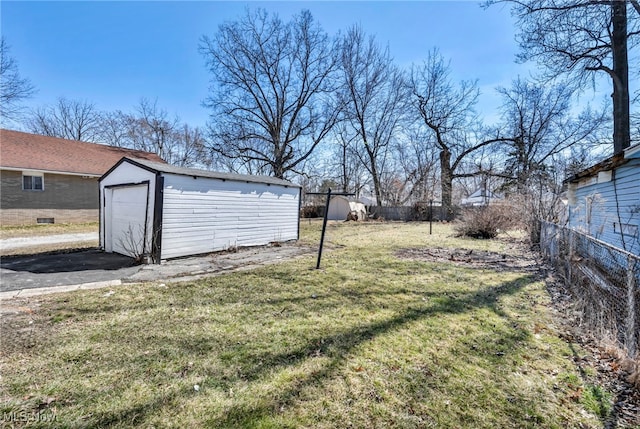 view of yard featuring aphalt driveway, a garage, an outdoor structure, and fence