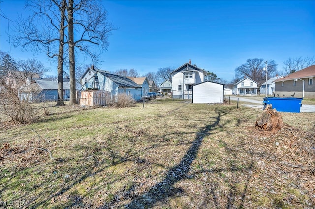 view of yard featuring a residential view, an outbuilding, and fence