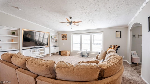 living room with ceiling fan, vaulted ceiling, ornamental molding, arched walkways, and a textured ceiling