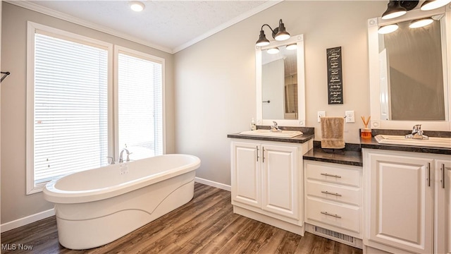 bathroom with a sink, a soaking tub, wood finished floors, and double vanity