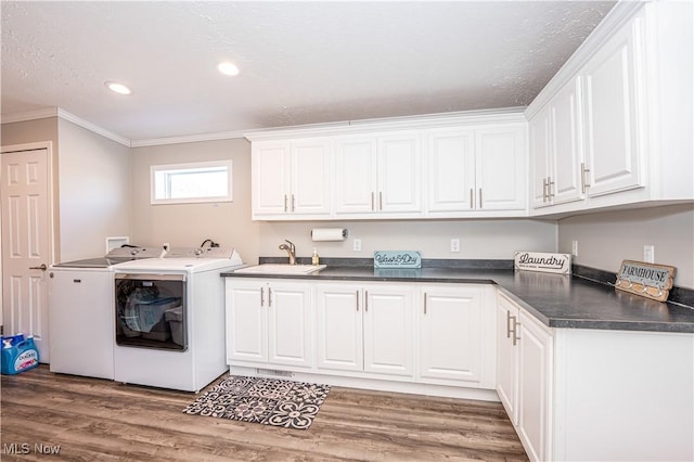 washroom featuring light wood-style flooring, a sink, cabinet space, separate washer and dryer, and crown molding