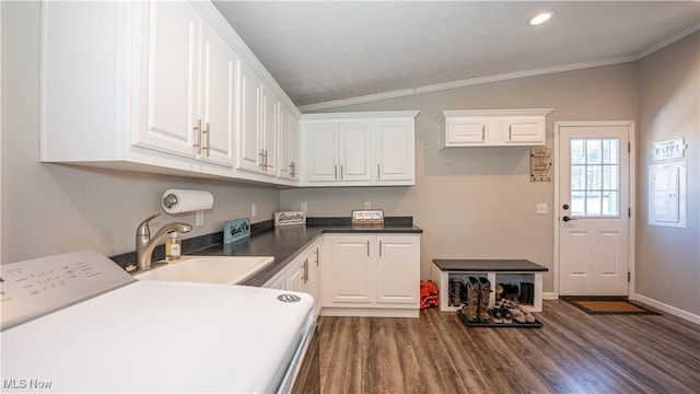 clothes washing area with dark wood finished floors, ornamental molding, cabinet space, and a sink