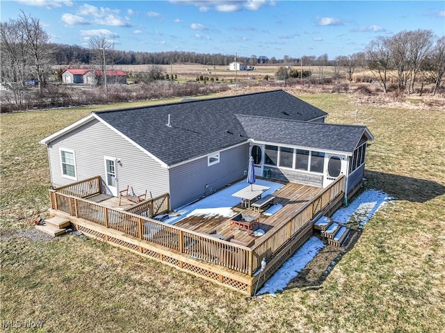 rear view of house with a wooden deck, a lawn, and a shingled roof