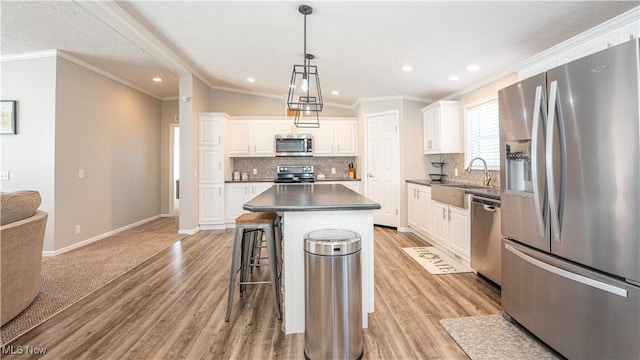 kitchen with white cabinetry, dark countertops, appliances with stainless steel finishes, and a sink