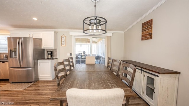 dining area with wood finished floors, plenty of natural light, a chandelier, and crown molding