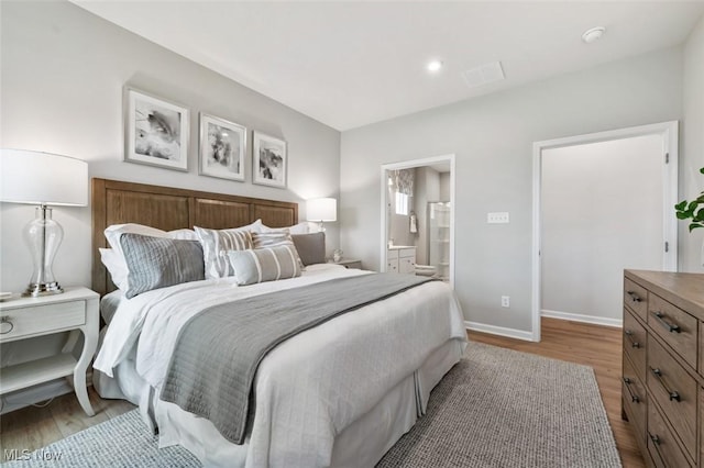 bedroom with baseboards, wood finished floors, and ensuite bathroom