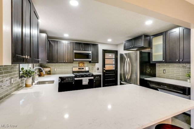 kitchen featuring a sink, stainless steel appliances, light stone counters, and tasteful backsplash