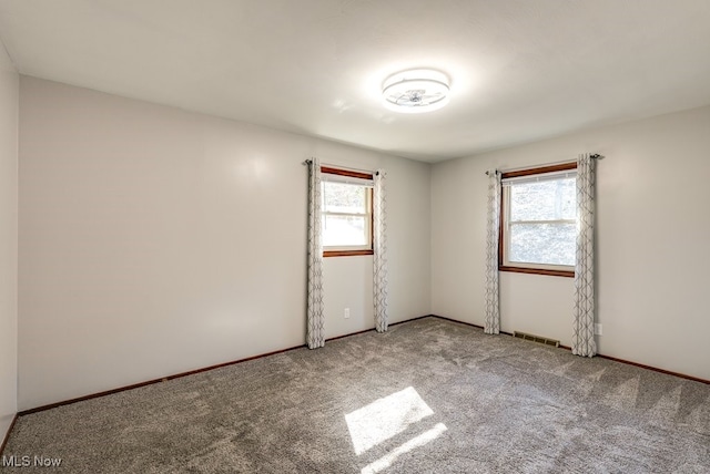 empty room featuring baseboards, visible vents, carpet floors, and a healthy amount of sunlight