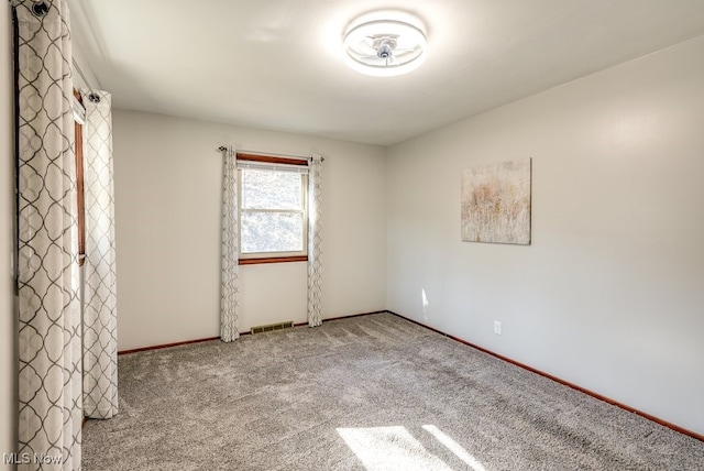 carpeted empty room with visible vents and baseboards