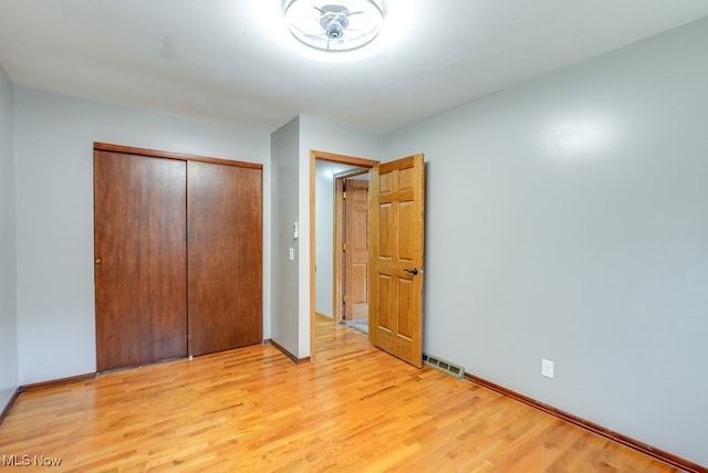 unfurnished bedroom featuring a closet, visible vents, baseboards, and light wood-style floors