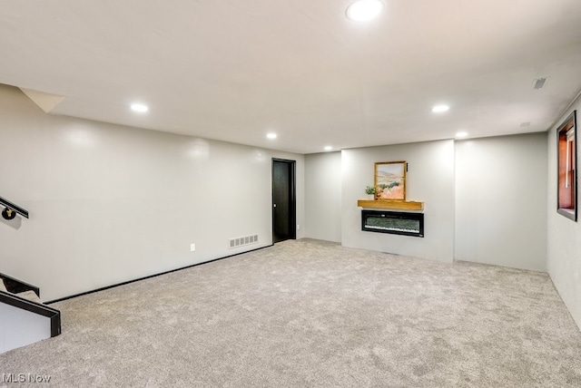 unfurnished living room with a glass covered fireplace, recessed lighting, carpet, and visible vents