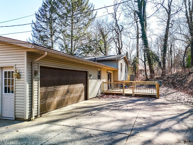 view of side of property featuring a deck, a garage, and driveway