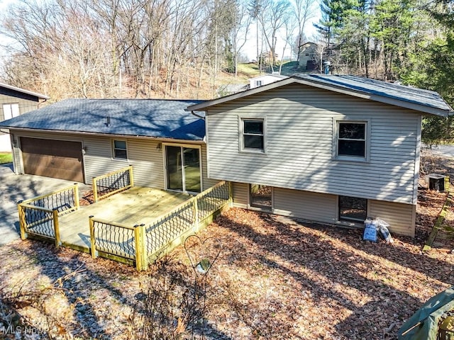 rear view of property with a deck, driveway, and a garage