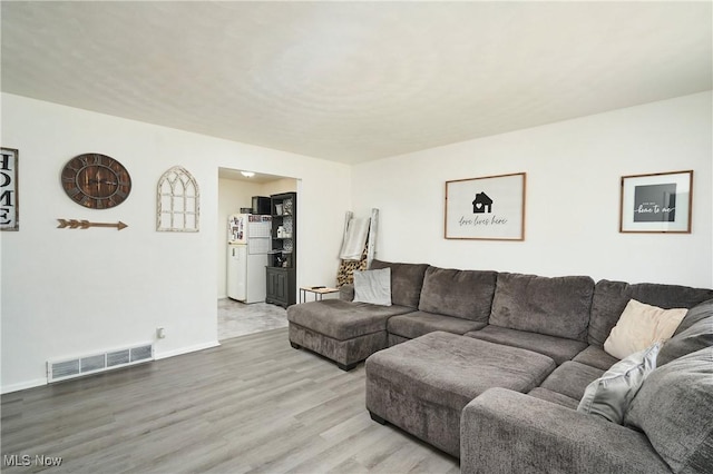 living room featuring visible vents, baseboards, and wood finished floors