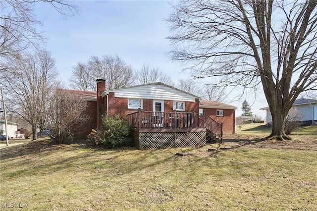 rear view of property with brick siding, a wooden deck, a chimney, and a yard