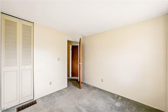 unfurnished bedroom featuring visible vents, carpet, and a closet