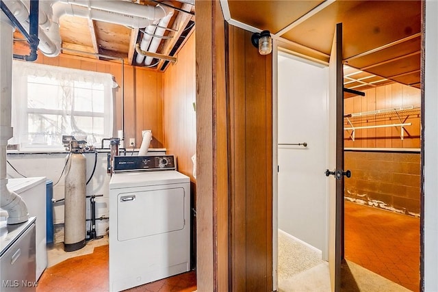 clothes washing area featuring laundry area, wood walls, and separate washer and dryer