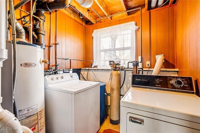 laundry area with water heater, laundry area, wood walls, and washing machine and clothes dryer