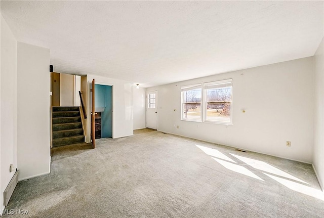 unfurnished living room featuring stairway, carpet flooring, and visible vents