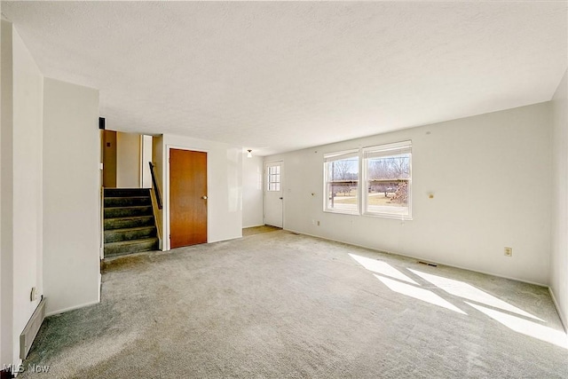 unfurnished living room with stairway, carpet floors, a textured ceiling, and visible vents