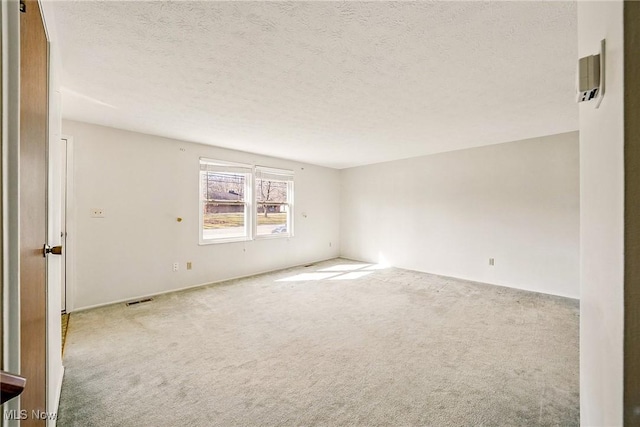 unfurnished room with visible vents, carpet floors, and a textured ceiling