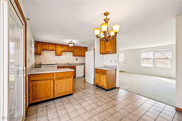 kitchen featuring white appliances, light countertops, brown cabinets, and light carpet