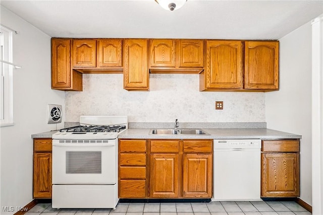 kitchen with white appliances, brown cabinetry, light countertops, and a sink