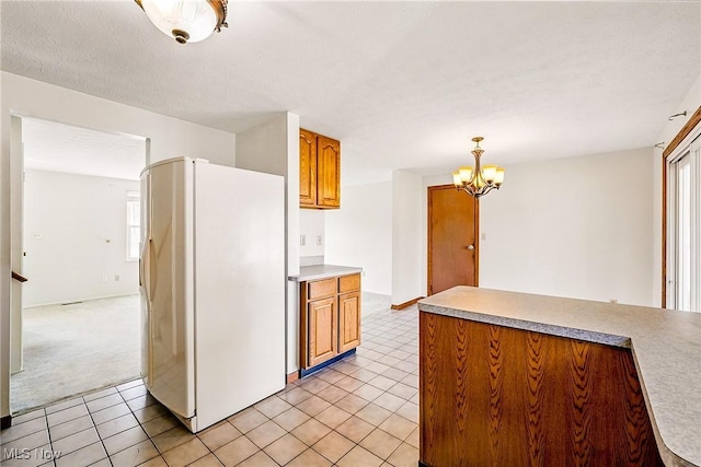 kitchen featuring a chandelier, light countertops, light tile patterned floors, brown cabinets, and white fridge with ice dispenser