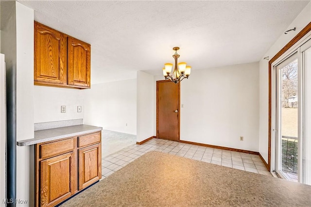 kitchen with decorative light fixtures, brown cabinets, an inviting chandelier, light tile patterned flooring, and a textured ceiling