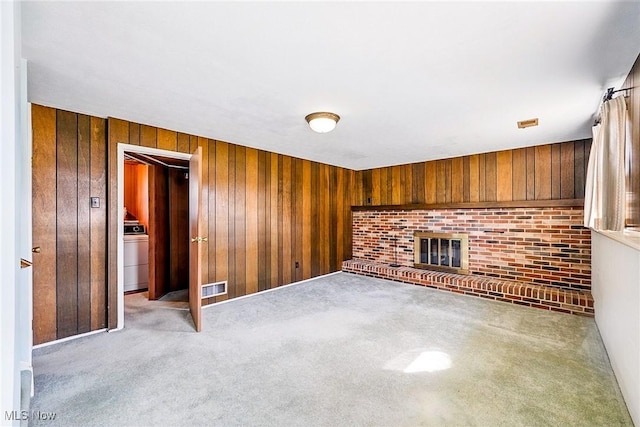 unfurnished living room with washer / clothes dryer, visible vents, and wood walls