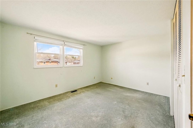 unfurnished bedroom featuring carpet flooring, visible vents, and a textured ceiling