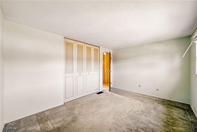 unfurnished bedroom with a closet, carpet, and a textured ceiling