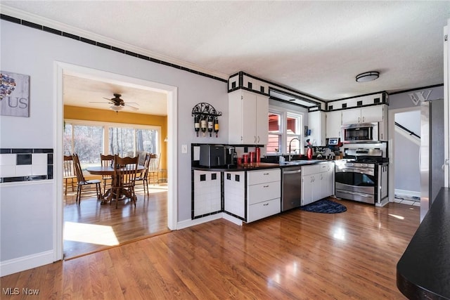 kitchen with dark countertops, dark wood-style floors, white cabinets, and stainless steel appliances