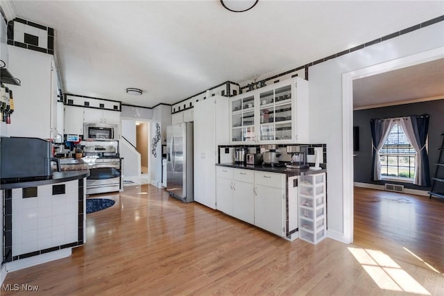 kitchen with visible vents, light wood-style floors, appliances with stainless steel finishes, white cabinetry, and dark countertops