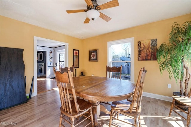 dining space with baseboards, light wood-type flooring, and ceiling fan