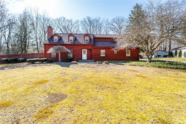 view of front of property with a chimney, a shingled roof, a front yard, and fence