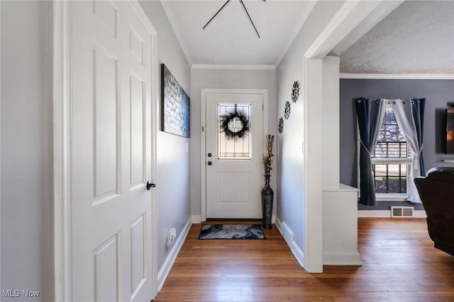 foyer featuring visible vents, ornamental molding, baseboards, and hardwood / wood-style flooring