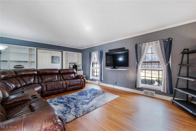 living area featuring visible vents, wood finished floors, baseboards, and ornamental molding