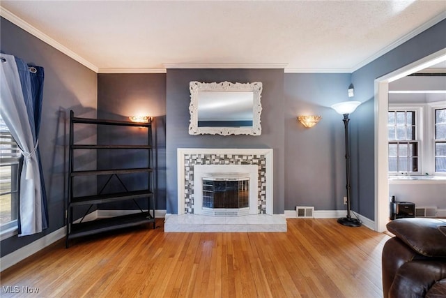 unfurnished living room with a wealth of natural light, baseboards, wood finished floors, and crown molding