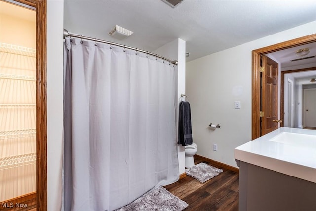 full bath with vanity, a shower with shower curtain, wood finished floors, visible vents, and toilet