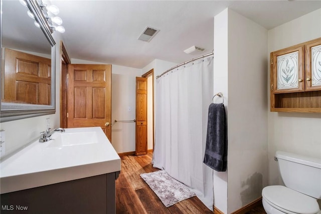 full bathroom with vanity, a shower with curtain, wood finished floors, visible vents, and toilet