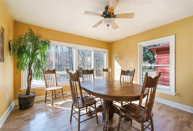 dining space featuring baseboards, a ceiling fan, and wood finished floors