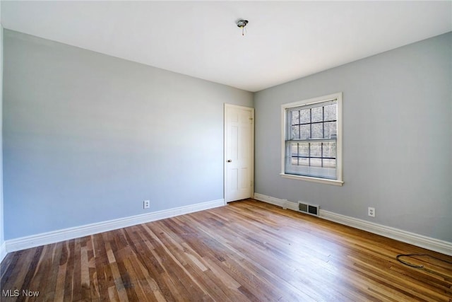 empty room with visible vents, baseboards, and wood finished floors