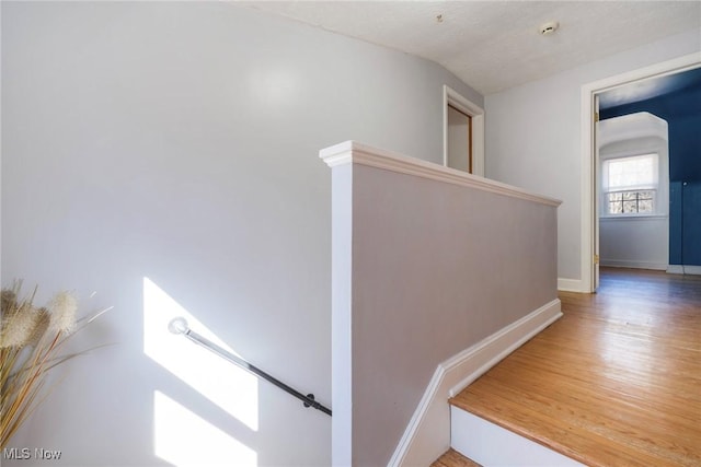 staircase featuring vaulted ceiling, baseboards, and wood finished floors