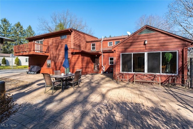 back of property with outdoor dining space and a patio